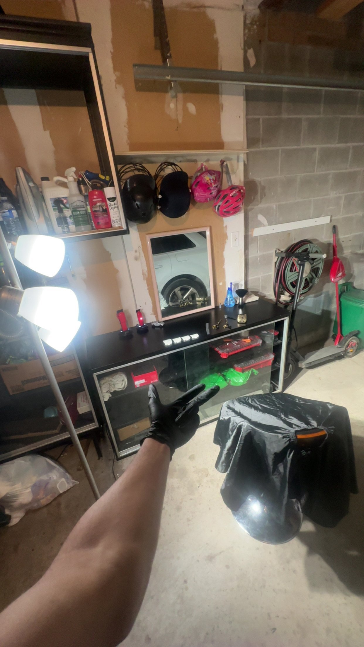 Garage workspace with black desk, bright LED lights, motorcycle helmets, sports equipment, and storage shelves