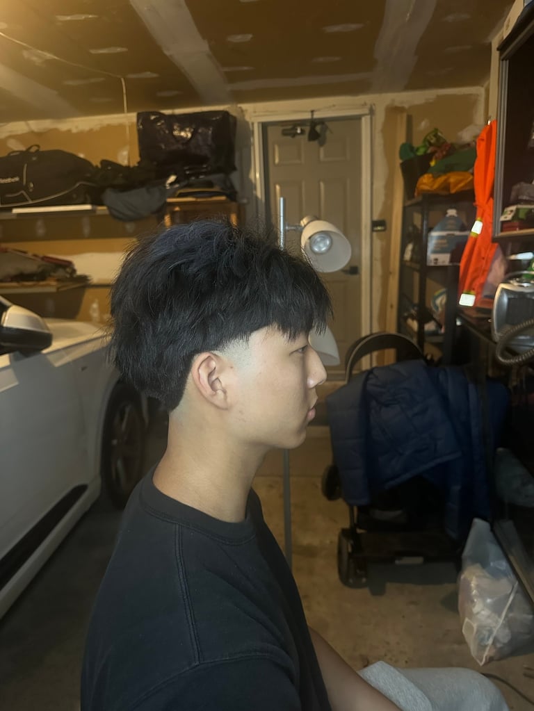 Person with black hair in profile wearing dark shirt inside cluttered garage
